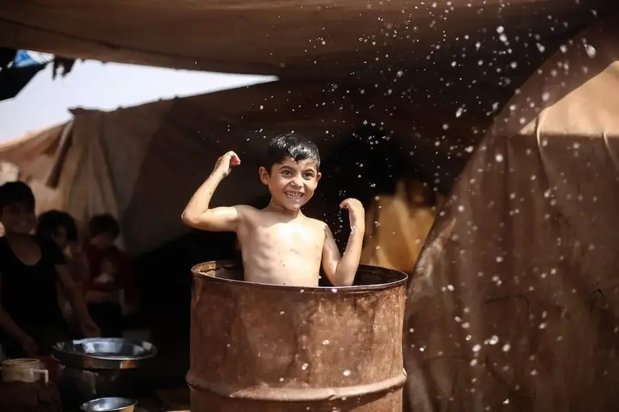 Enfant prenant un bain dans un vieux baril rouillé.
